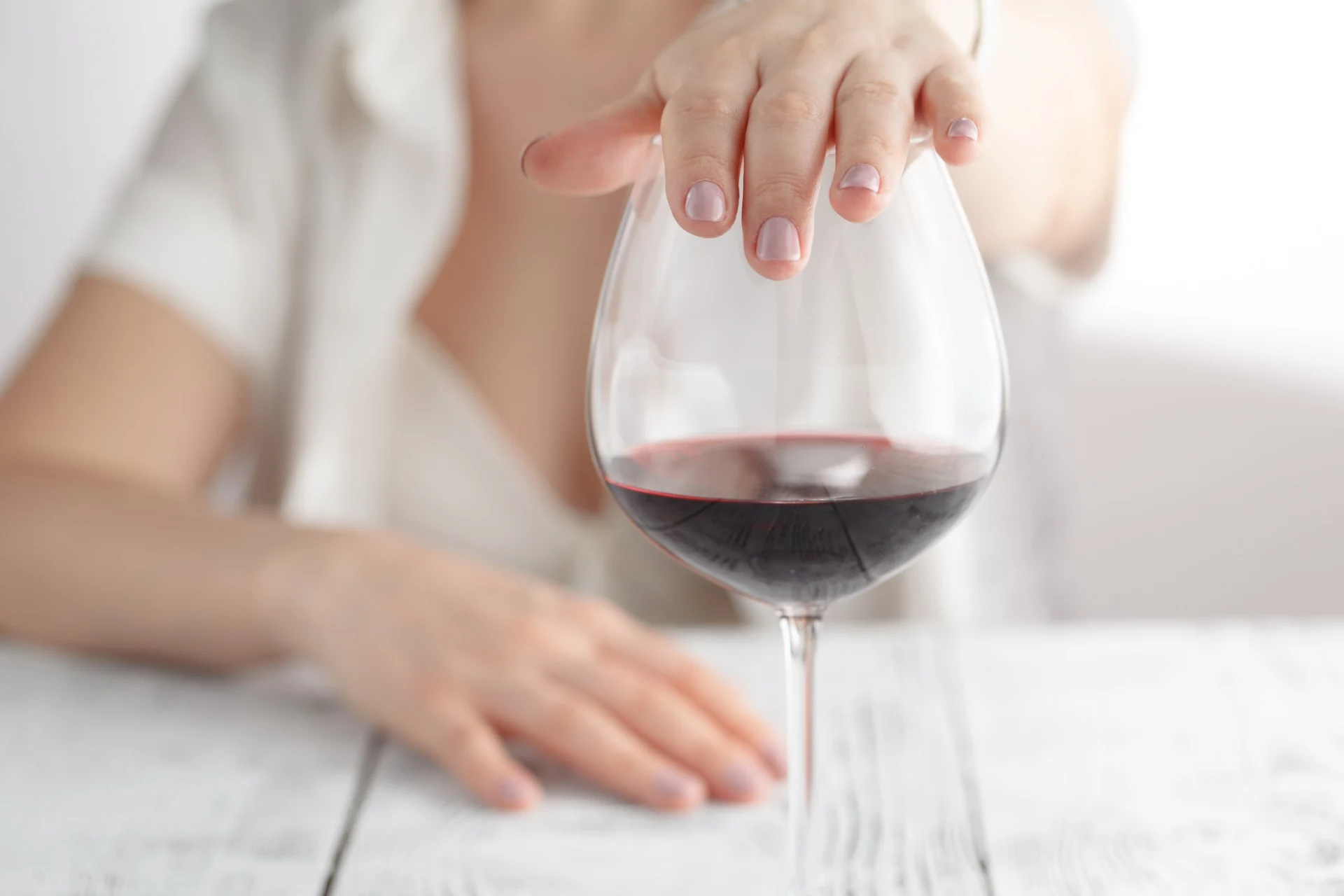 woman refusing glass of red wine essential wellness trend